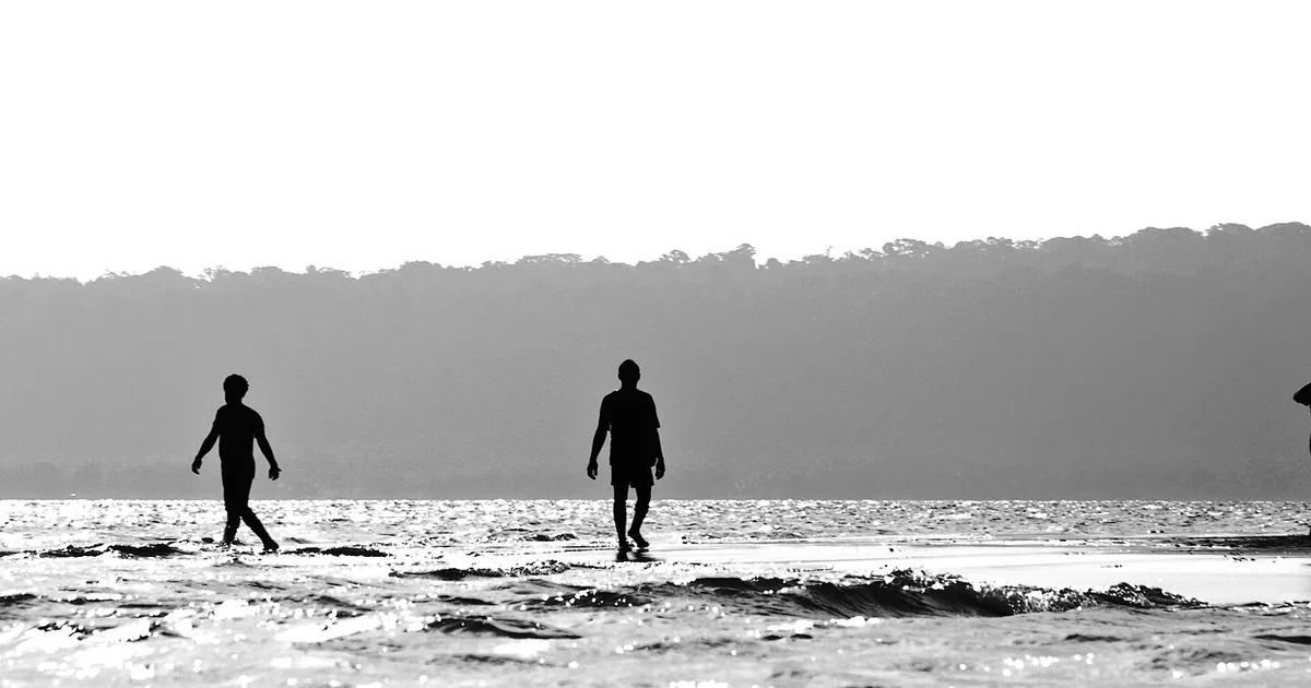 Figures walking on the shoreline at low tide, Vanuatu